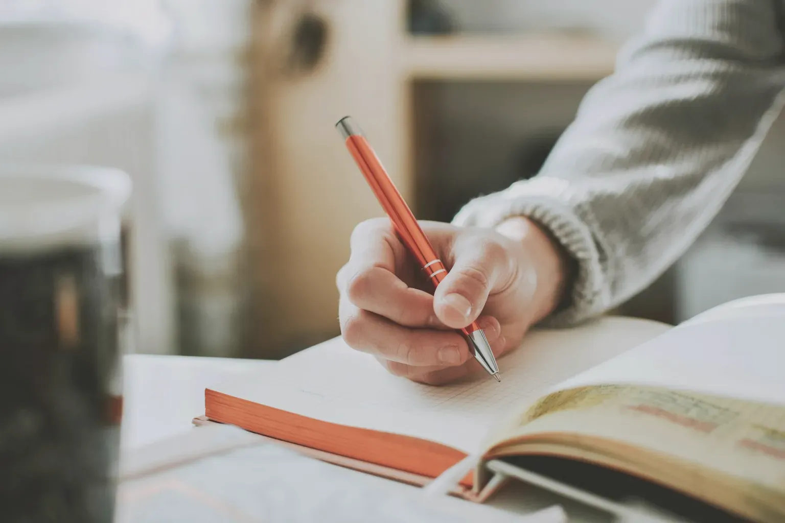 A hand writing a short note in an open notebook