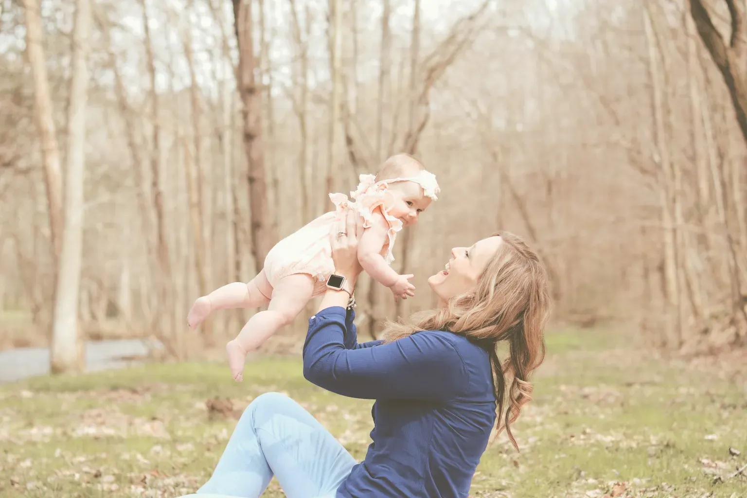 A mother lifting her baby in a forest clearing