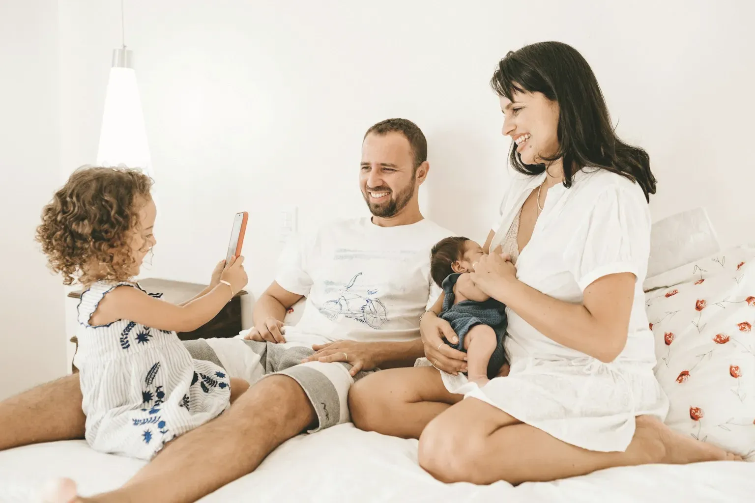 A family with two children relaxing on a white bed
